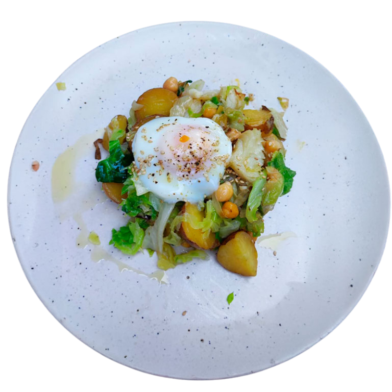 Prato de legumes salteados com batata, grão-de-bico e ovo escalfado, servido em prato branco.